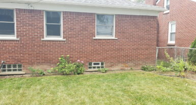 Brick house with a small garden and lawn, ideal for landscaping services and lawn maintenance in Macomb County.
