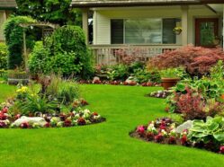 Lush landscaped garden with vibrant flower beds and well-maintained green lawn in front of a cozy house, perfect for outdoor living.